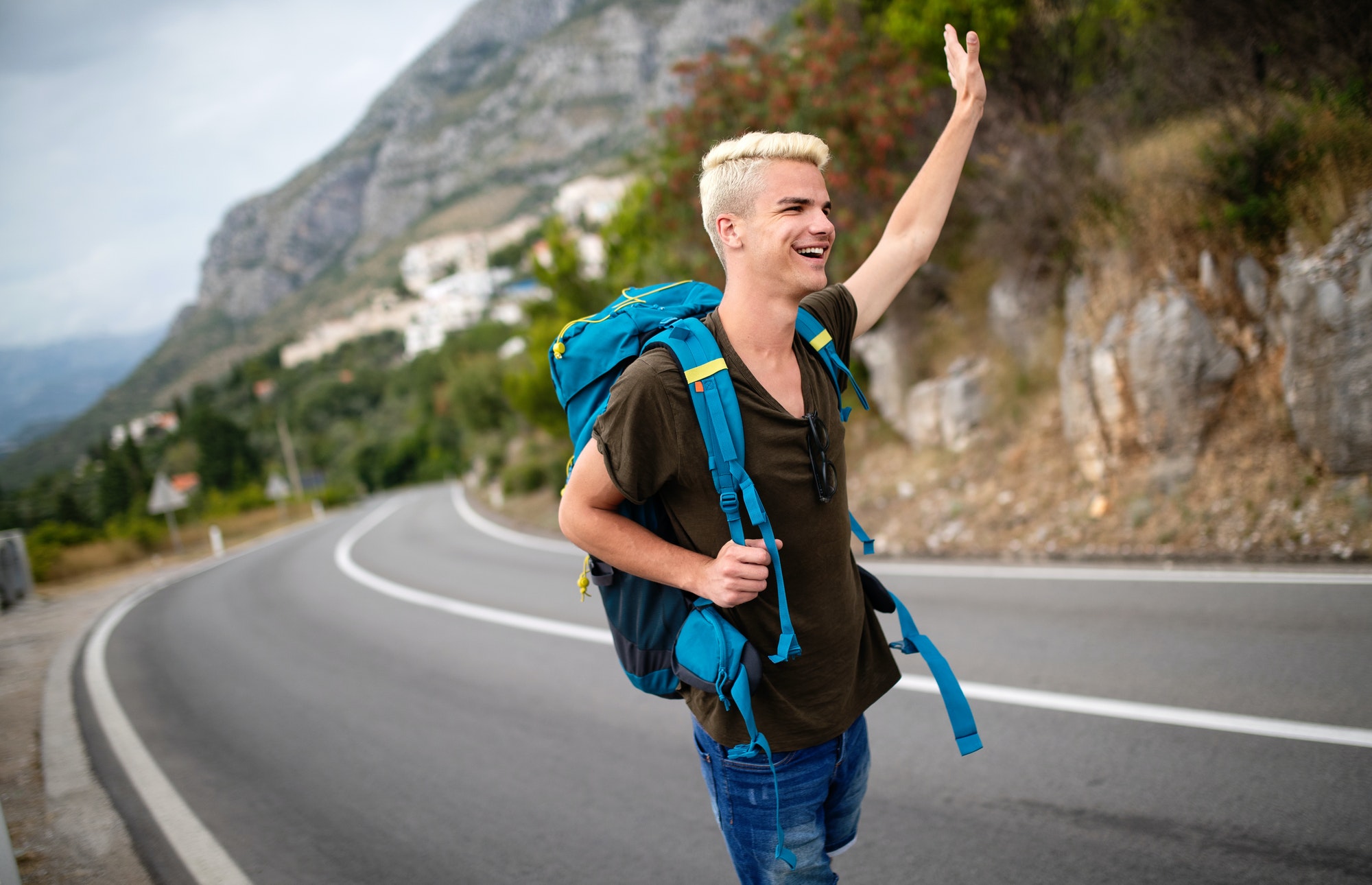 Travel man backpacking hitchhiking on road trip hitching a ride from car