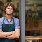 Hes a proud shop owner. A handsome young store owner standing in the entrance of his shop.
