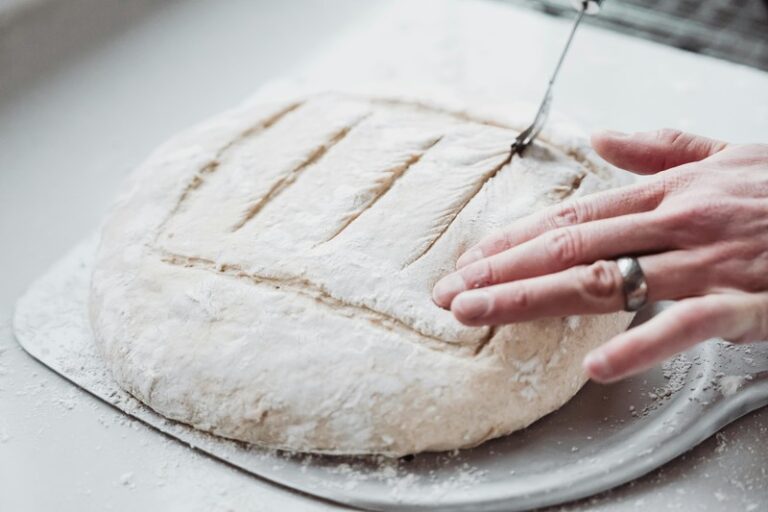 Baker shaping sourdough dough in a floured banneton basket