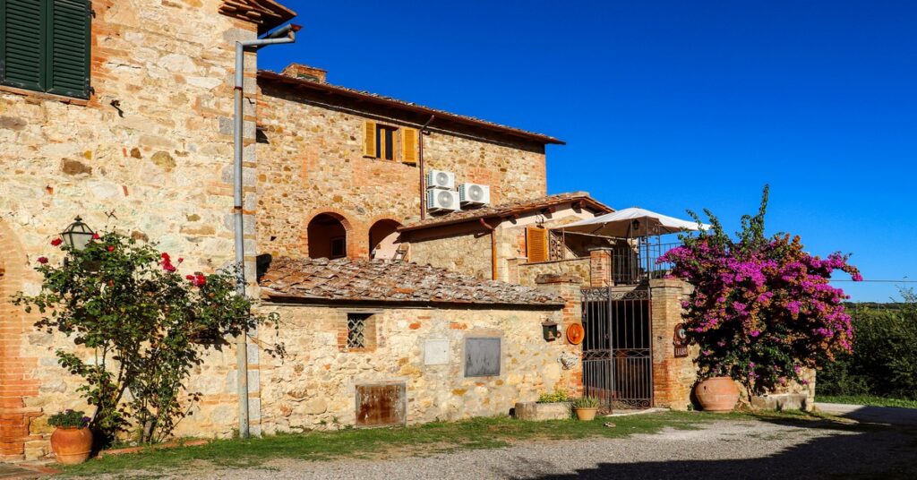 A rustic Italian farmhouse surrounded by vineyards and olive groves in the Tuscan countryside