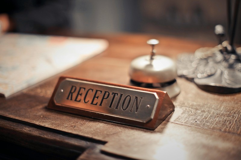 A guest checking in at the reception desk of an Italian agriturismo, with a rustic interior