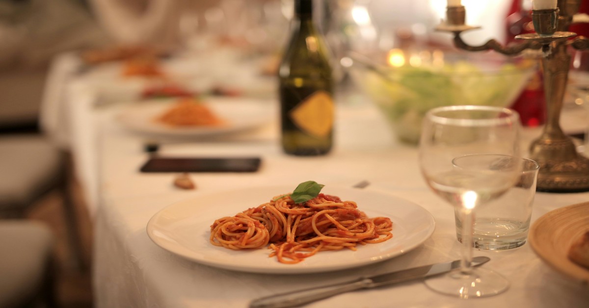 Wooden farm table with plates of handmade pasta, red wine, and bread at an agriturismo in Tuscany