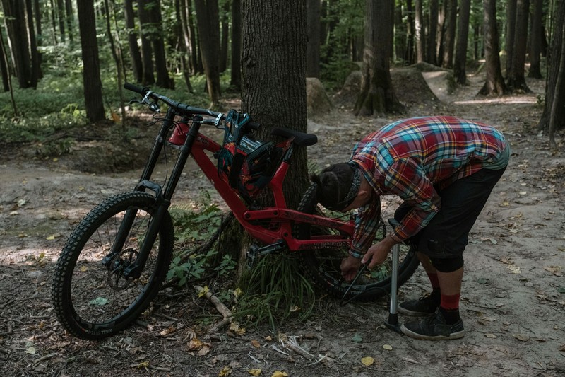 Portable bike repair kit with tire levers and pump resting on a gravel road beside a bicycle wheel