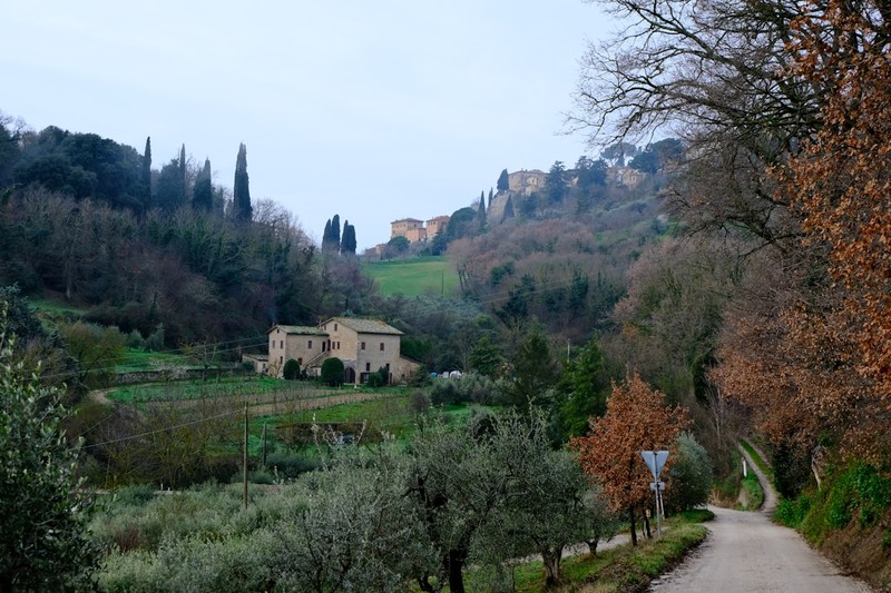 Electric bicycle parked beside a stone farmhouse in rural Italy with hills and olive trees