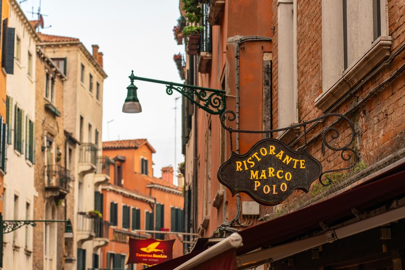 Narrow cobblestone street in an Italian village with a tavern sign and warm lights