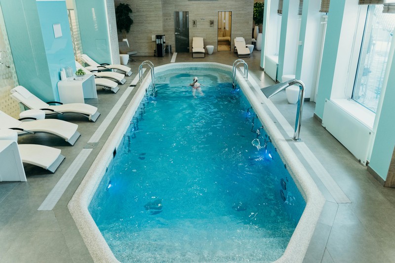 An indoor thermal spa pool in Italy with stone arches and warm lighting