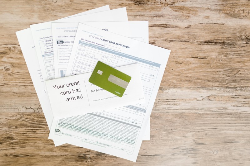 A passport, credit card, travel insurance papers, and pen spread on a wooden table