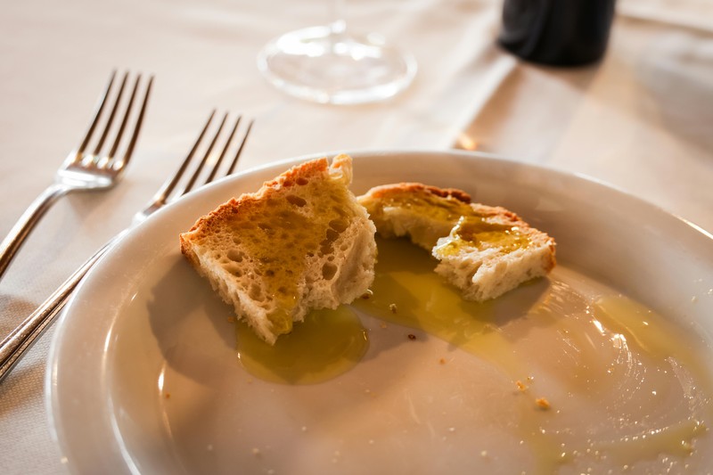 A person tasting olive oil from a small glass at a Puglia mill