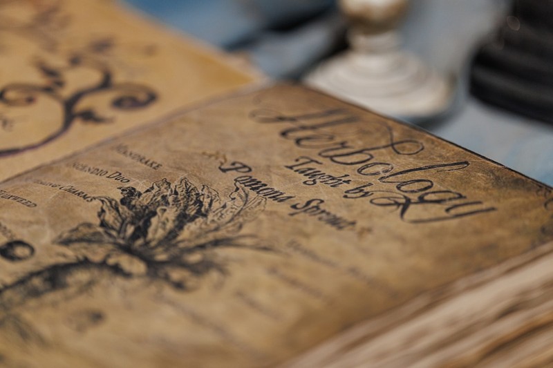 A leather travel journal and pen resting on a wooden table in a farmhouse kitchen