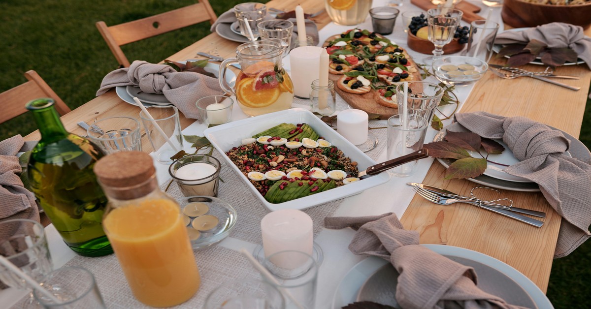 Long wooden table set for a large group outdoors at a Tuscan agriturismo with vineyards in the background
