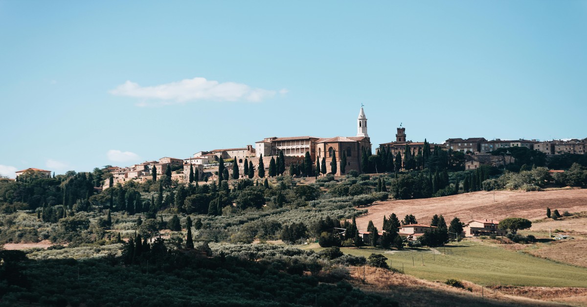 A scenic view of a Tuscan agriturismo with rolling hills and olive trees under a sunny sky