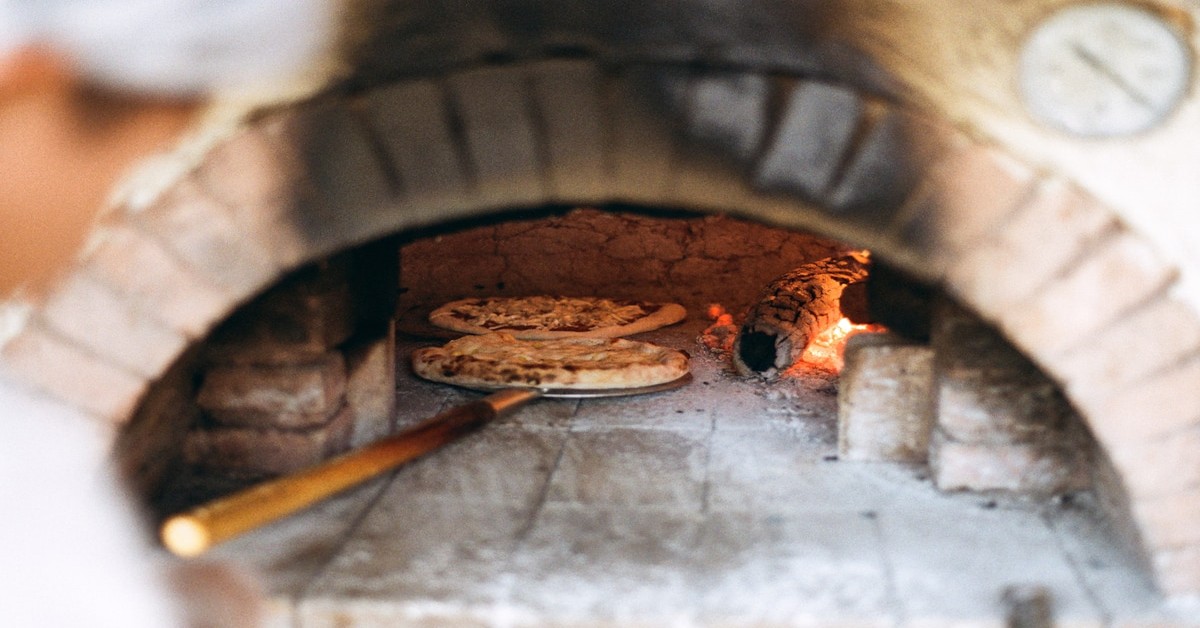 Glowing wood-fired oven with Italian bread loaves inside